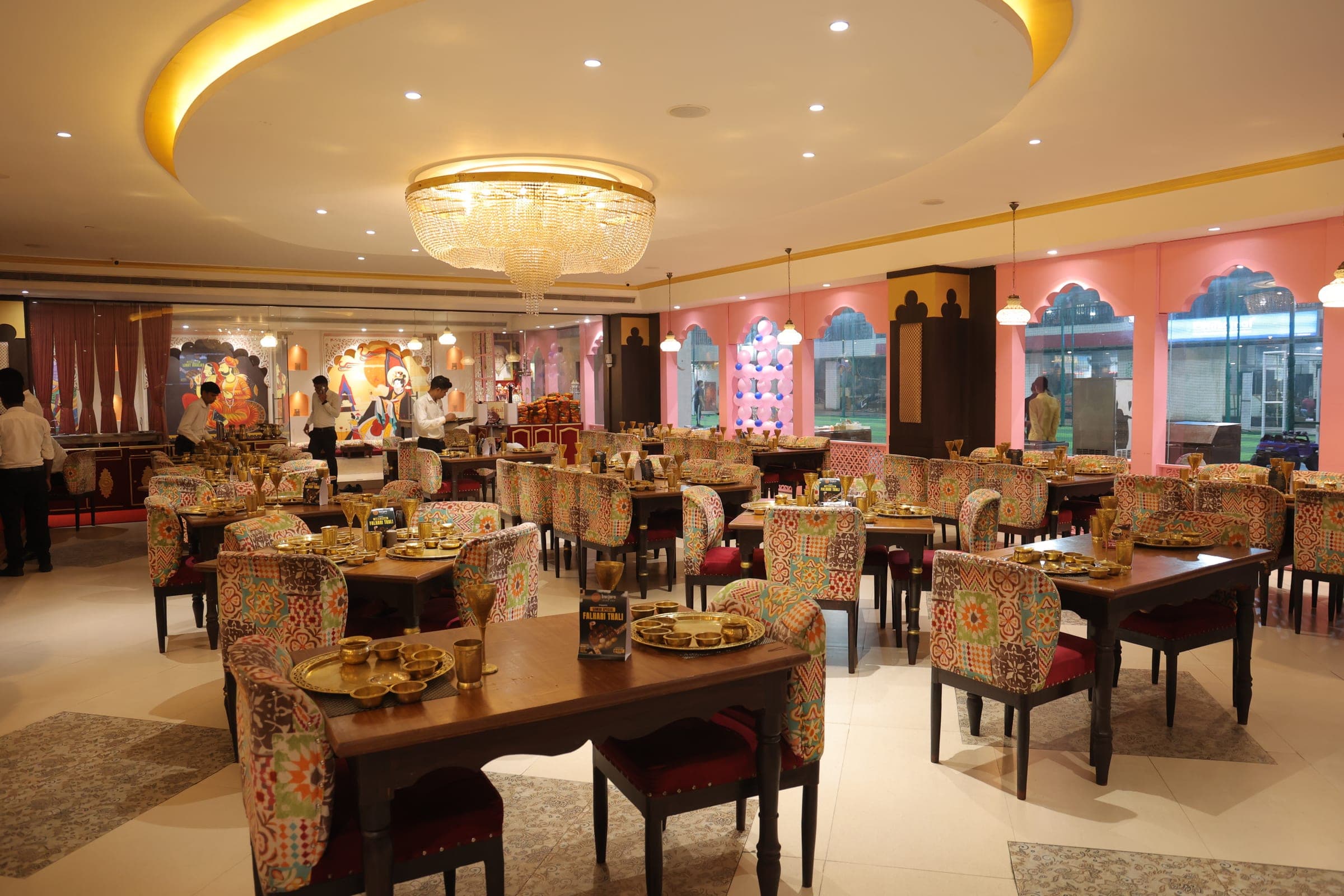 Warm dining room at Banjara Sonari with brass tableware, patterned chairs and a chandelier